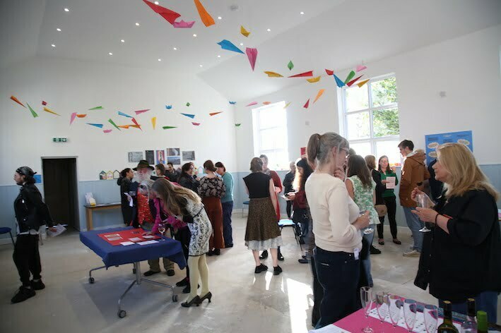 A while hall with colourful decorations and groups of people talking